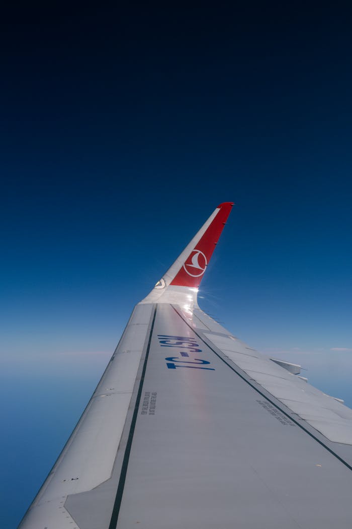 View from an airplane showing the wing against a clear blue sky, ideal for travel themes.